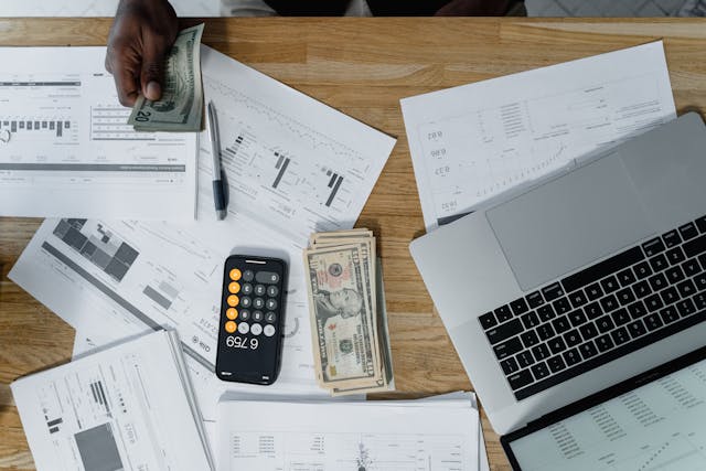 a desk with cash, a calculator, and papers